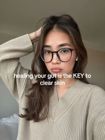 Woman in glasses touching her hair, text: healing your gut is the key to clear skin