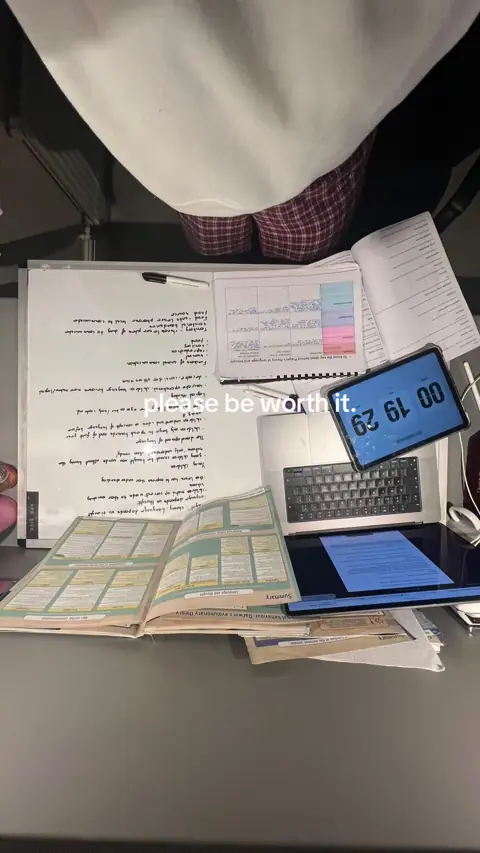 Top-down view of a lap in pyjamas with revision notes, a laptop and a timer